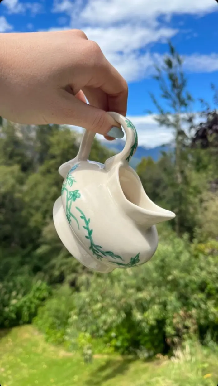 A handmade ceramic mug held up outdoors